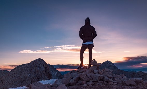 En man står vid klippor och tittar på solnedgången